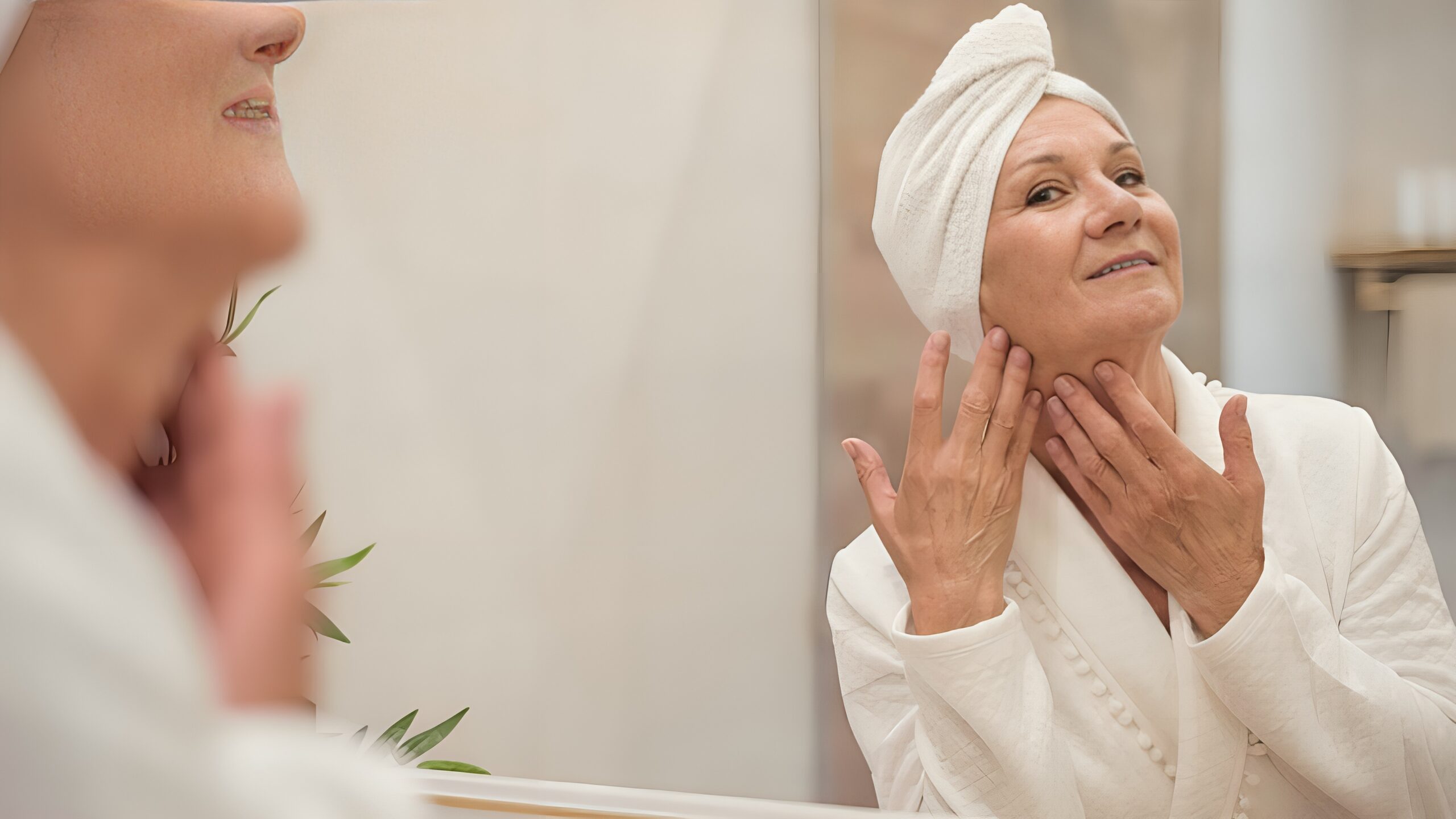 Woman in a spa robe admiring her refreshed, glowing skin in the mirror at Eternite Spa