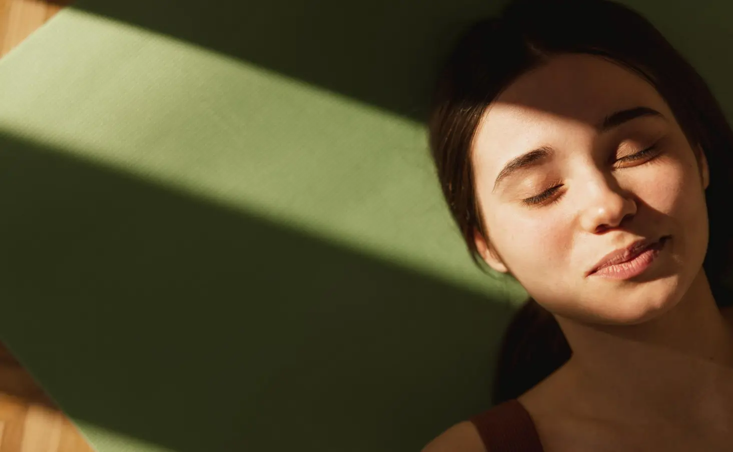 Woman relaxing in warm natural sunlight with eyes closed, highlighting healthy, glowing skin and a calm skincare lifestyle.